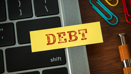There is sticky note with the word DEBT. It is as an eye-catching image.