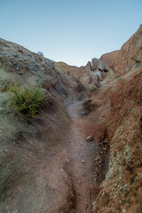 Rocky canyon trail with rugged terrain, sparse vegetation, and clear blue sky, showcasing the beauty of natural landscapes and outdoor adventures in a serene environment