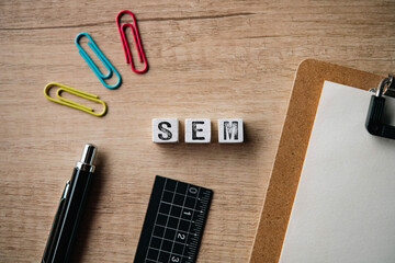 There is wood cube with the word SEM. It is an abbreviation for Search Engine Marketing as...