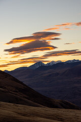 Majestic mountain landscape at sunset, showcasing vibrant clouds and rugged peaks, with a serene...