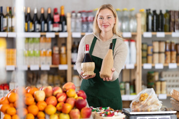 Positive female seller offers to buy bottles of wine in supermarket