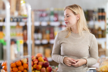 Portrait of girl shopper with a shopping cart choosing some products in a supermarket