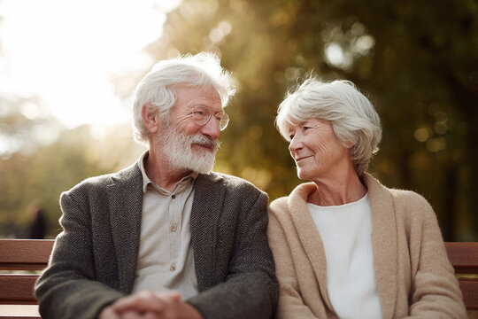 Elderly couple in love, sitting on a park bench, gazing affectionately. Captures enduring love, companionship, and happy senior lifestyle. Perfect for retirement, healthcare, and relationship themes.