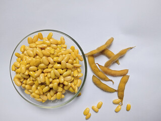 Fresh yellow soybeans in a clear glass bowl on a plain white background. Shiny and neatly arranged beans, perfect for food ingredients, healthy eating, and vegetarian lifestyle concepts.