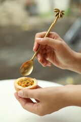 Woman eating passion fruit at table outdoors, closeup