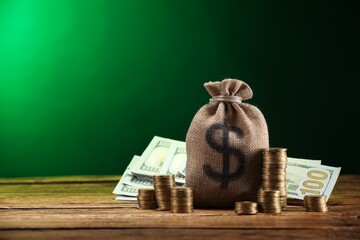 Bag, dollar banknotes and stacked coins on wooden table against green gradient background, space for text