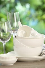 Different clean dishes on wooden table against blurred green background