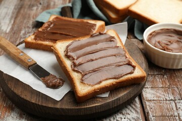 Sandwiches with chocolate butter and knife on wooden table, closeup