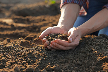 Man holding pile of soil in field, closeup