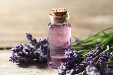 Natural essential oil and lavender flowers on wooden table, closeup