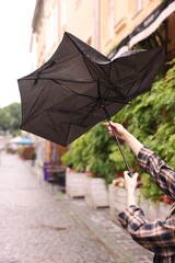 Woman with broken umbrella on city street, closeup