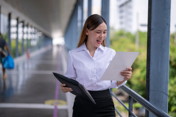 Excited businesswoman celebrating success while reading documents in a modern office building