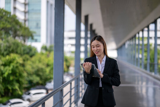 Smiling businesswoman using digital tablet in modern office building corridor