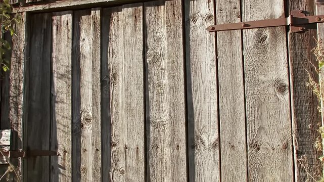 Weathered, vertical wooden planks forming a door with rusty hardware