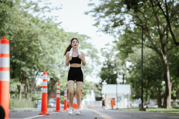 A young woman is jogging outdoors in a park, wearing workout clothes. She is surrounded by nature...