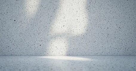 Empty speckled concrete room with light shining through a window casting soft shadows on the floor and wall