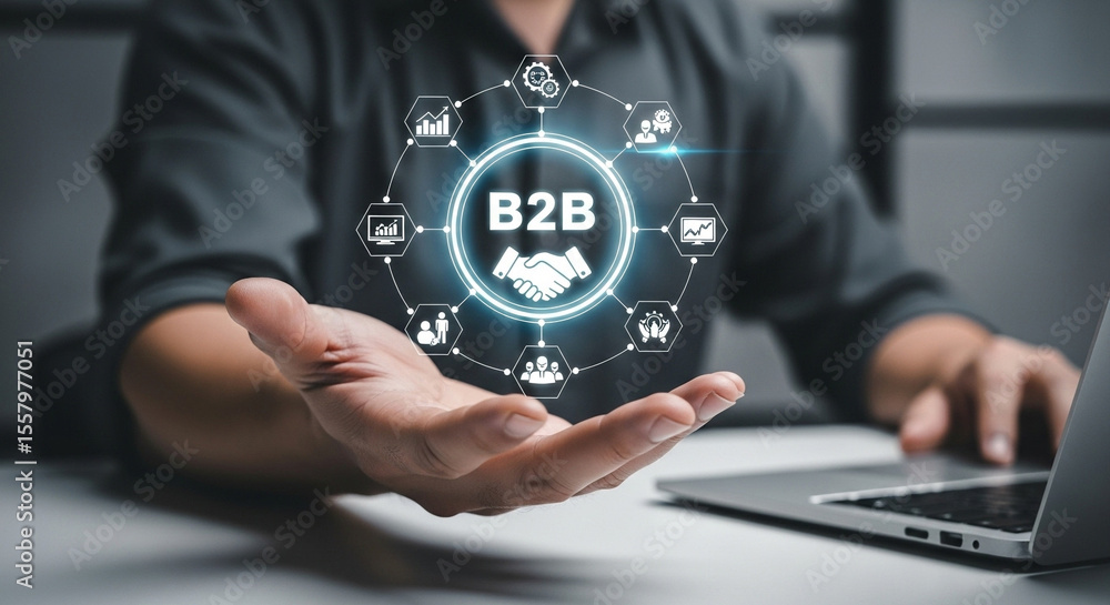 Poster person holding b to b graphic with icons around it in front of a laptop on a white surface