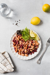  Mixed salad of canned beans with lemon and greens on a plate for healthy eating. Plant protein
