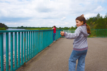 Happy girls, sisters enjoying a walk by the lake on a cloudy day.