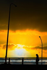 夕焼け空の下の陸橋を渡る通行人