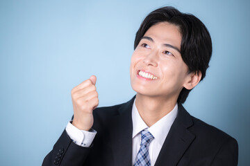 スーツを着たビジネスマンの若い男性水色　思い付く、閃くアイデアのポーズクローズアップ