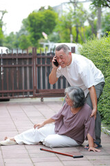 Elderly Asian woman slips and falls on the floor in front of her house. Husband calls for help to call an ambulance. Falls in the elderly.