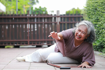 Elderly Asian woman slips and falls, she lies on the floor, calls for help and rushes to the hospital. Falls in the elderly.