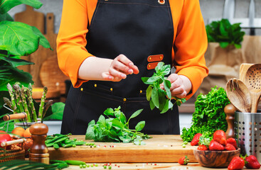 Chef preparing fresh herbs and vegetables for a healthy vegan meal in a vibrant kitchen space