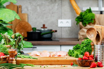Raw chicken breast fillet and healthy meals in a cozy kitchen filled with fresh herbs and vibrant vegetables
