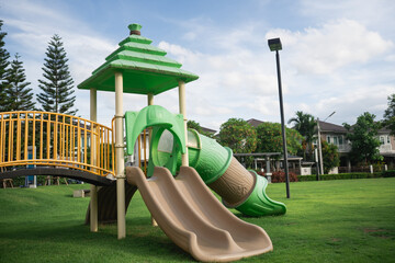 Colorful playground structure featuring green slides and climbing area, set in a lush green park...