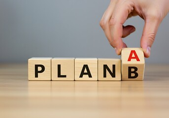 Hand changes wooden blocks from plan b to plan a, showing decisionmaking