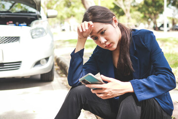 Asian woman calls emergency services because her car broke down and was parked on the side of the road. Car accident insurance. Transportation concept.