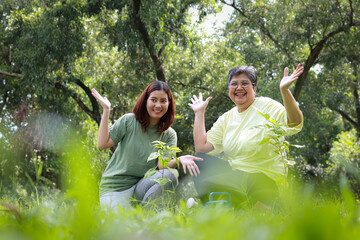 Volunteer mother and daughter smiling happily are helping to plant seedlings in the forest to help restore the forest. Save the world. Plant trees to reduce global warming. Green ecosystem.