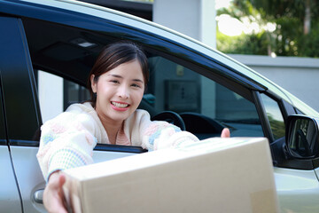 Asian young woman in car holding parcel box in car with smile and happiness. Delivery service concept.