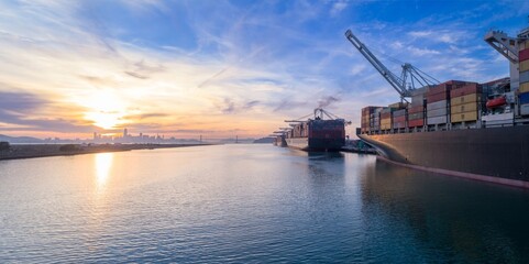 Cargo ships docked at the Port of Oakland, California, USA, are being loaded with shipping...