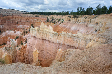 Looking out from the Queens Garden Trail at red rock hoodoo formations, in colors of pink, tan, and...