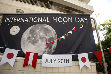 Moon Day Banner Display: A festive banner announces "International Moon Day", its surface adorned with celestial graphics, set against a backdrop of a building.