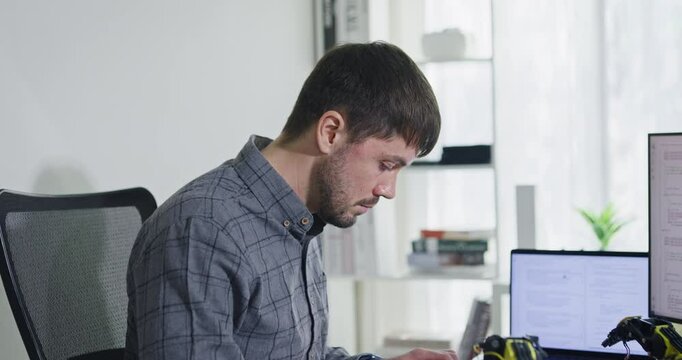 Portrait confident smiling male programmer working with robotics code AI software and looking at camera in tech office. Artificial intelligence dashboard, robotics, user interface, machine learning.
