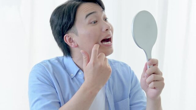 鏡で歯・口を気にする男性