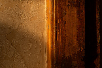 Rustic Textured Plaster Wall with Aged Wooden Board Detail in Natural Light