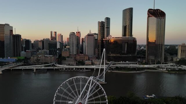 Brisbane CBD, Queensland, Australia: 4K Aerial Sunset Image Featuring City Skyline, Skyscrapers, Brisbane River, The Wheel of Brisbane, and South Bank Cultural Precinct in Warm Evening Light