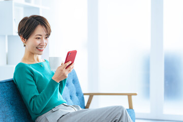 モダンなリビングでスマホを見るミドルエイジ女性