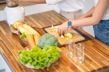 Close up of hand picking up apple and other holding blender making smoothie drink at kitchen counter