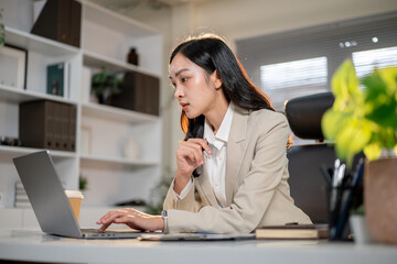 Close up of asian businesswoman or female office worker looking intently at laptop on working table.