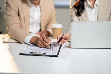Close up of businessman and woman pointing in clipboard discussing work at office's working table.