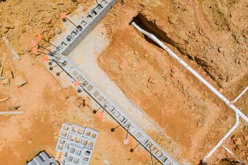 Workers are digging out trench for plumbing installation at construction site in works foundation...