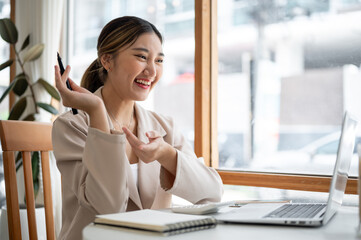 Pretty asian woman talking explaining with hand during video call or meeting on laptop at cafe table