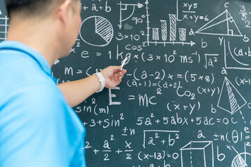 Teacher pointing at mathematical equations on chalkboard, concept of education, learning, science and instruction