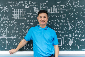 Asian male teacher standing in front of chalkboard filled with math formulas, education, teaching and learning concept