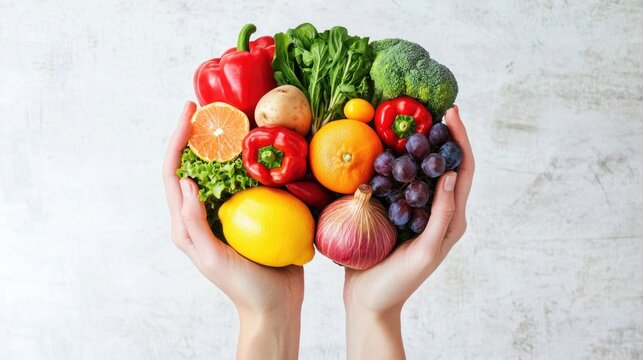 Hands holding a colorful assortment of fruits and vegetables against a light background.